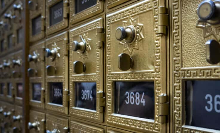 Gouden postkasten met slot en nummerindeling in een postgebouw.