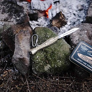 Gentlemen’s Hardware Vissers Zakmes naast blikje, outdoor bij kampvuur en stenen.